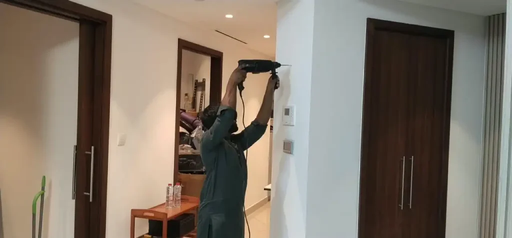 Handyman drilling in wall to hang a frame