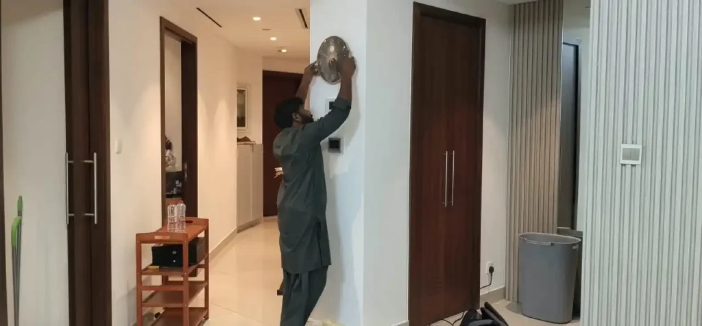 Handyman in Downtown Dubai hanging a clock on wall