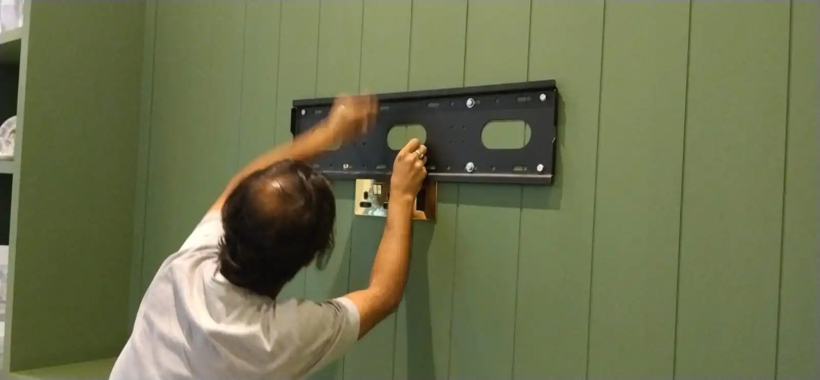 Handyman fixing tv bracket to mount tv on wooden tv panel
